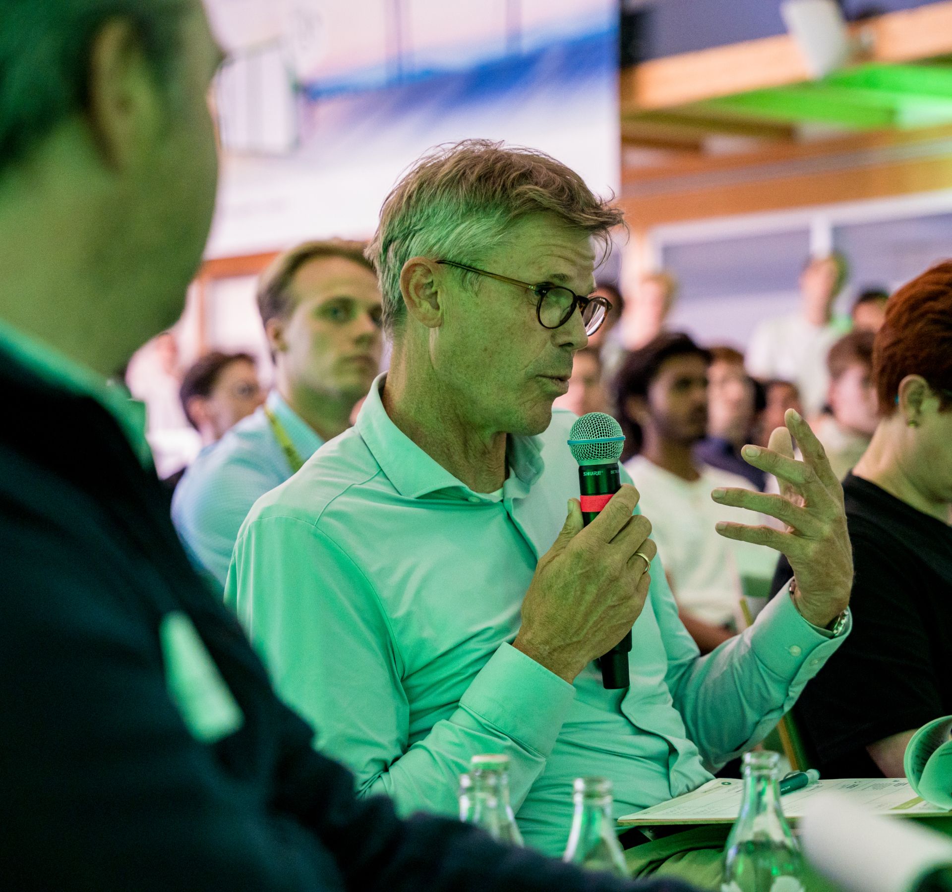 Corporate representative asking a question with a microphone during a panel discussion at a R-Factory event