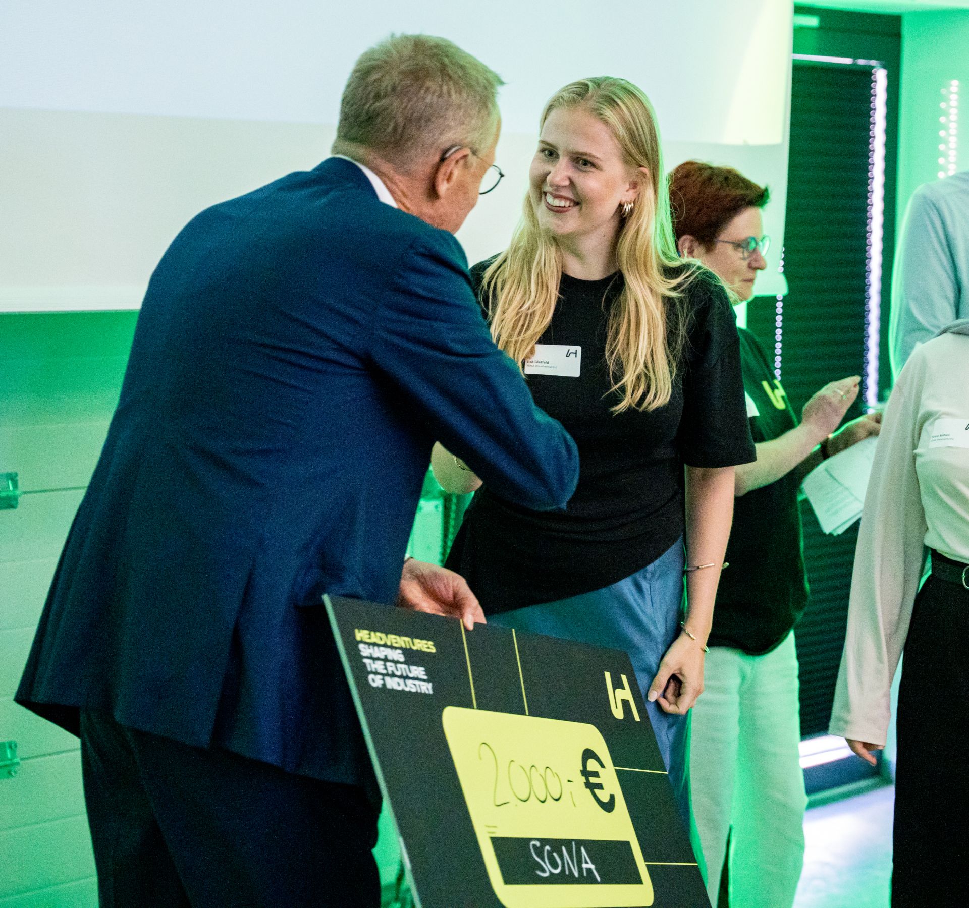 Award ceremony at HeadVentures: startup team SONA receives a €2,000 prize check from a jury member.